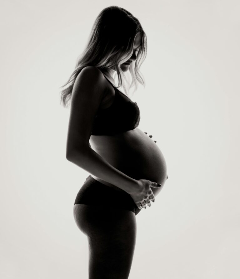 Silhouette of a pregnant woman in lingerie, expressing motherhood and contemplation.
